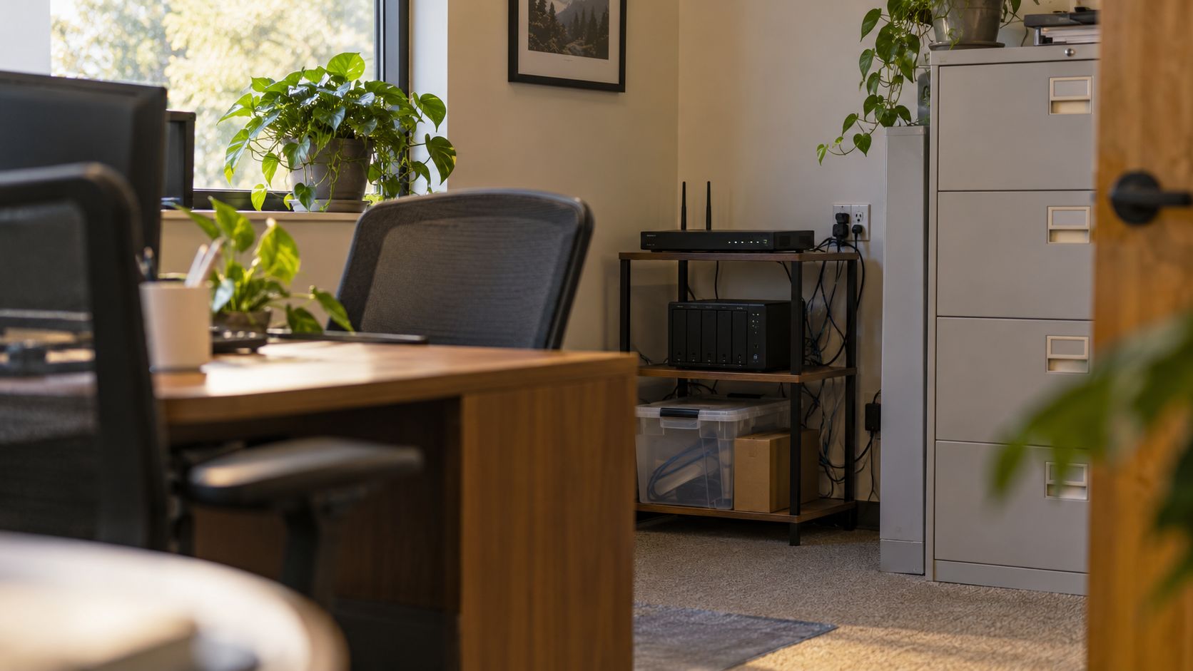 Small office corner with a router and network storage box on a shelf beside a filing cabinet